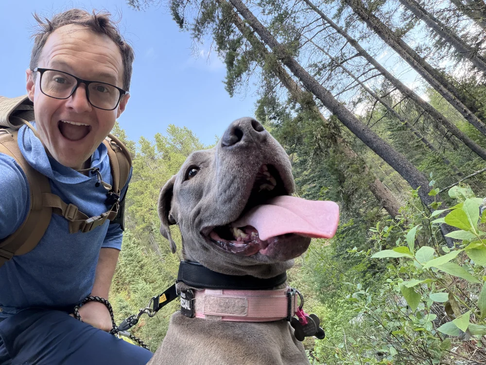 Brad Hart and his dog Kona on a forest hike, both grinning